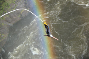 Bungee jumper above the Zambezi River and rainbow