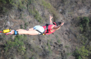 Side view of a bungee jumper diving above the gorge